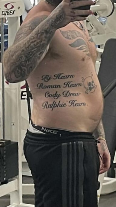 Week 1 Tattooed man in gym, showing side profile with text tattoos on torso.